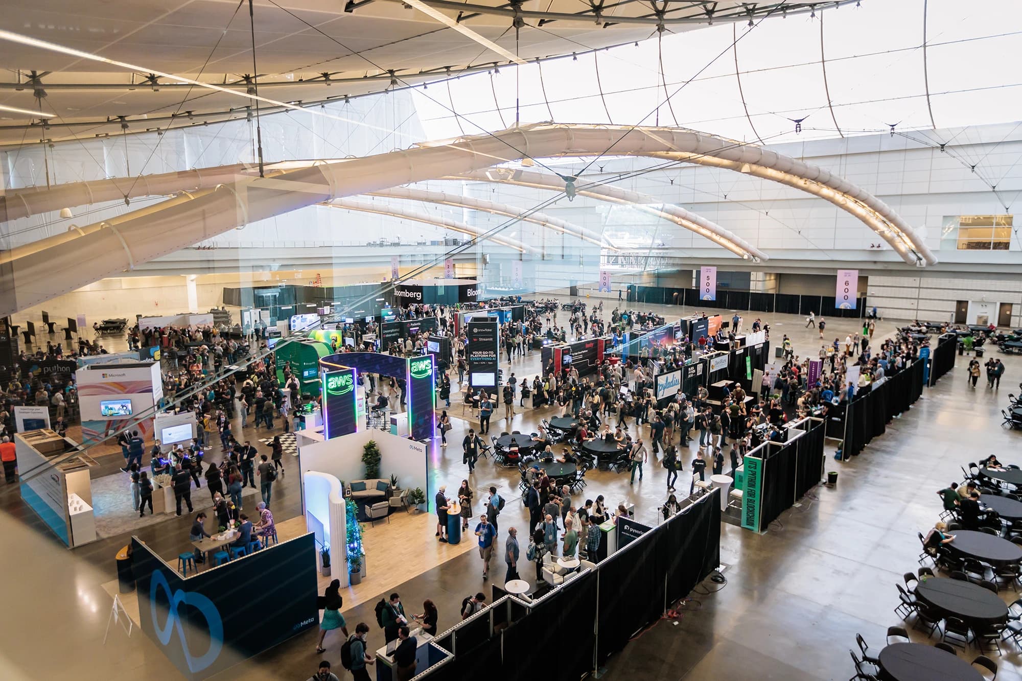 PyCon 2024 exhibit hall with sponsor booths and conference attendees
