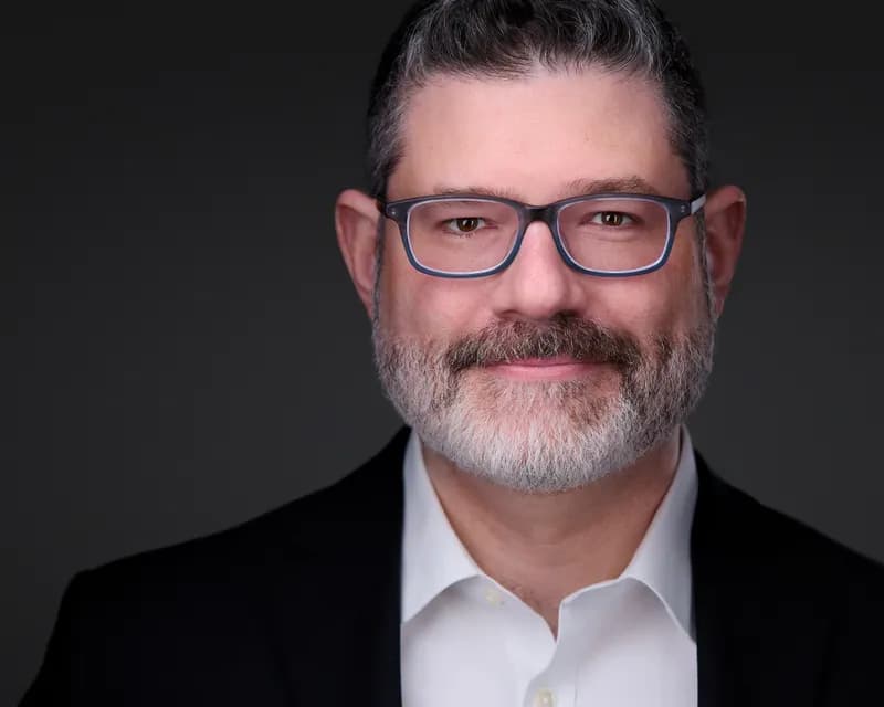 Corporate headshot of male professional with neutral background