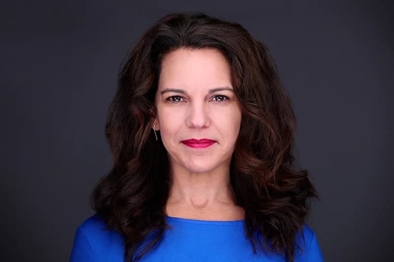 Professional business headshot of a woman against a clean neutral studio background