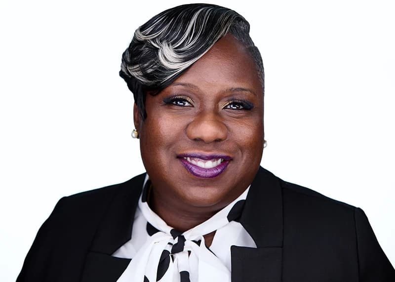 Professional headshot of woman with styled hair and statement earrings