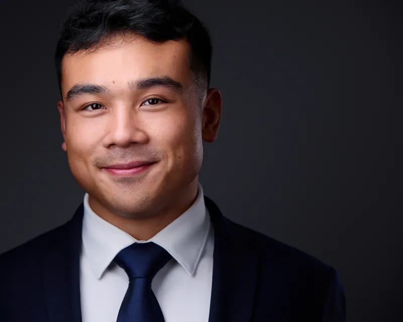 Professional headshot of male business professional in dark background