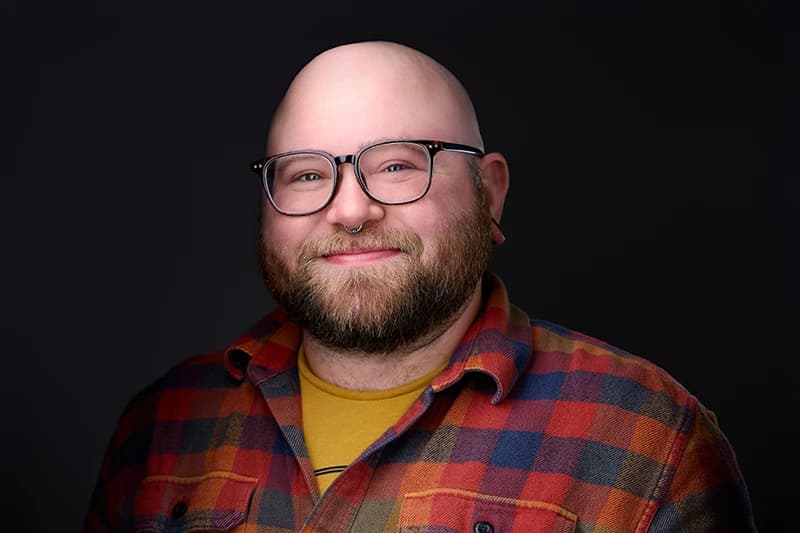 Male therapist headshot with a warm expression on a dark background - Pittsburgh counseling practice photography