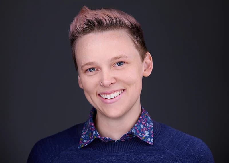Warm therapist headshot with genuine smile on a dark studio background - Pittsburgh counseling practice photography