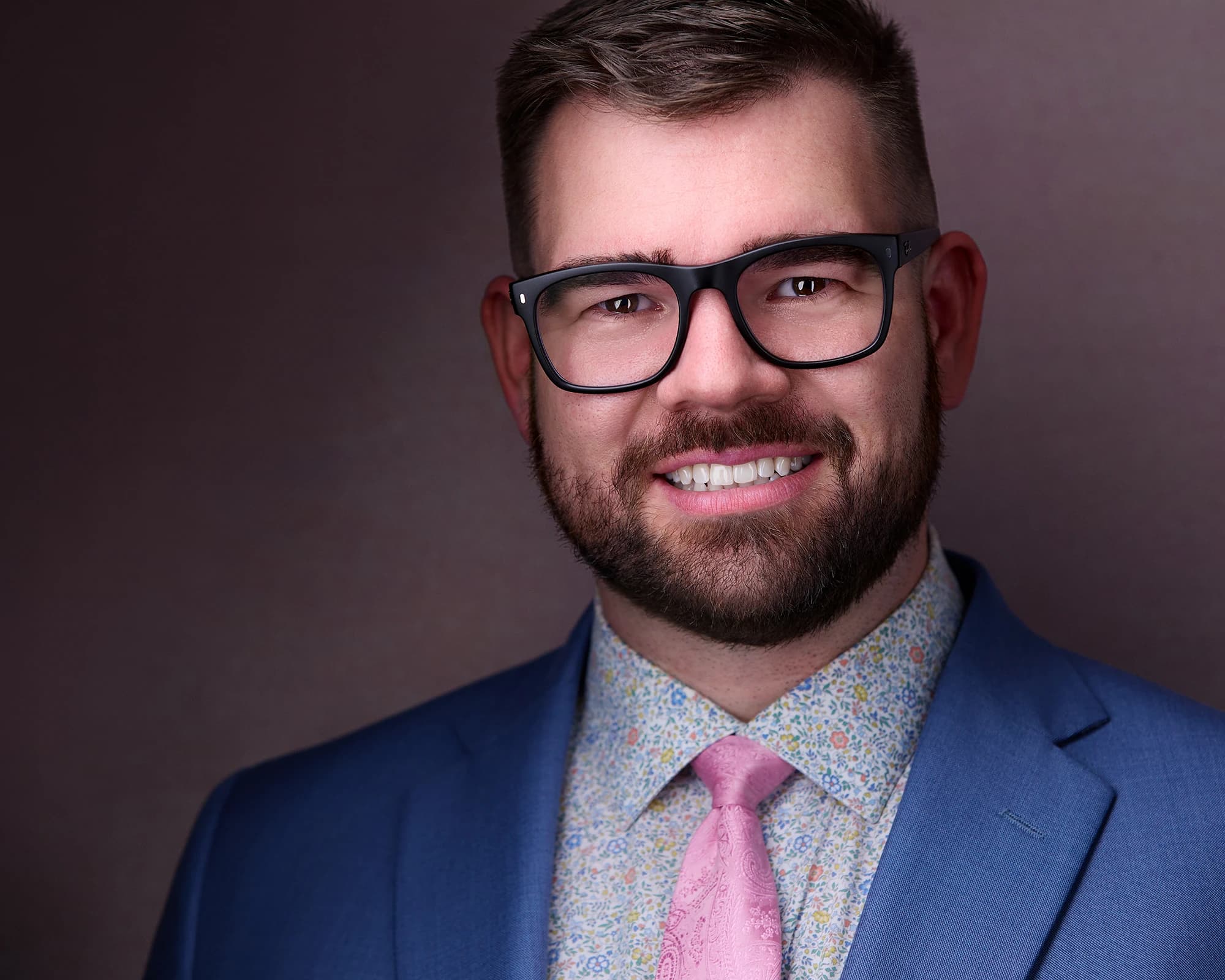 Male headshot poses with neatly trimmed facial hair