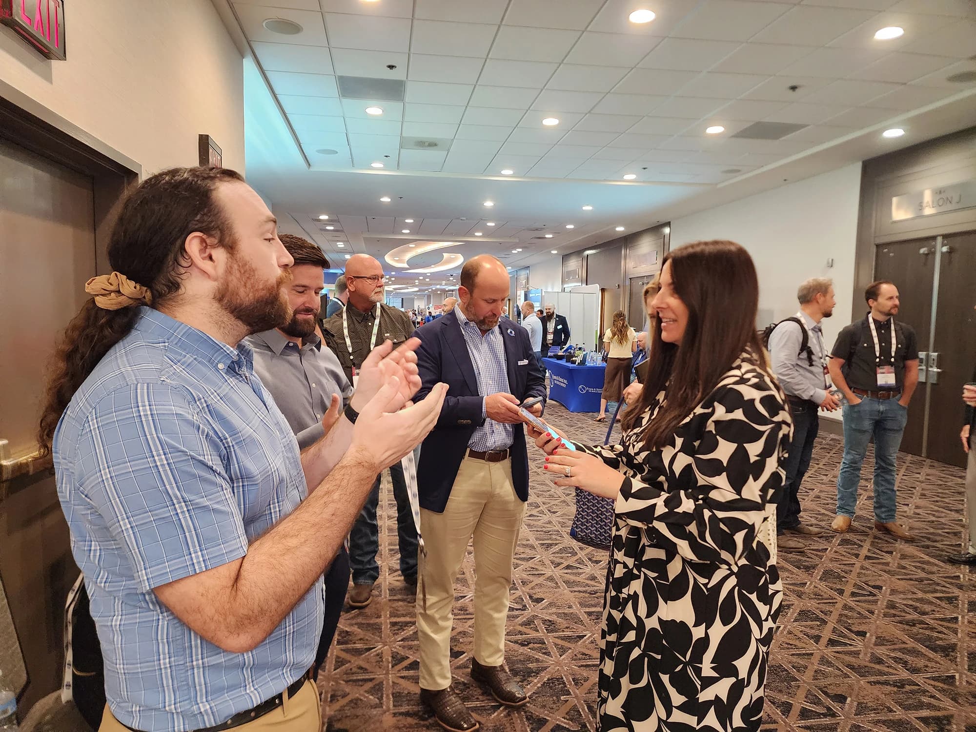 Exhibitor team talking with attendees waiting in line at a conference headshot booth activation